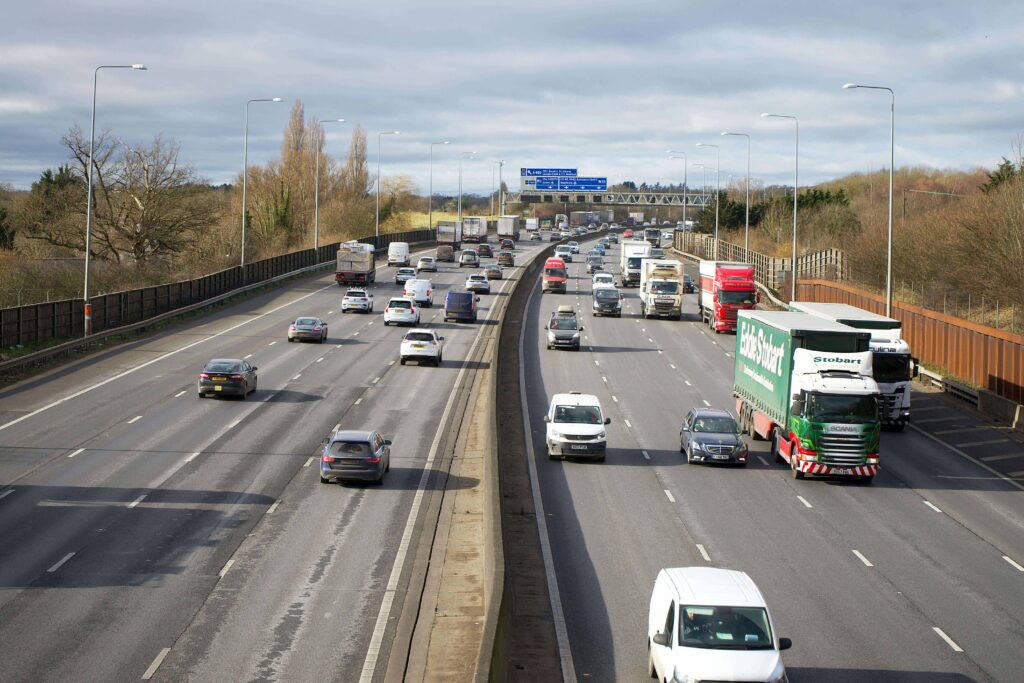 Image shows a motorway in the UK with lots of traffic including lorries. 