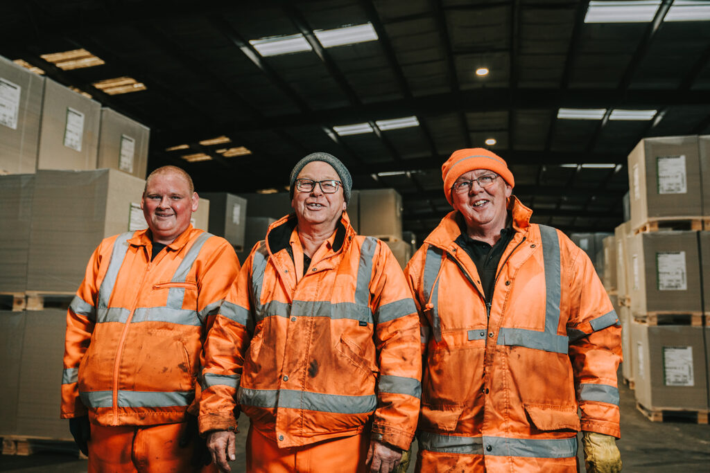 Image shows three men wearing high visibility jackets and trousers working in a warehouse near Immingham